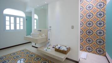 Un baño con lavamanos doble, un espejo grande, pared con diseño y suelo de baldosas.