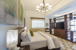 A hotel room with a large bed, a TV, a chandelier, and artwork on the walls. - Delfina Boutique Hotel (Mérida)