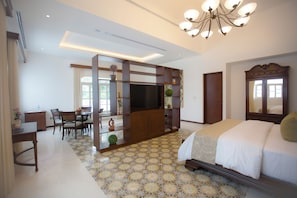 A hotel room with a bed, a TV, a desk with chairs, and a decorative screen. - Delfina Boutique Hotel (Mérida)