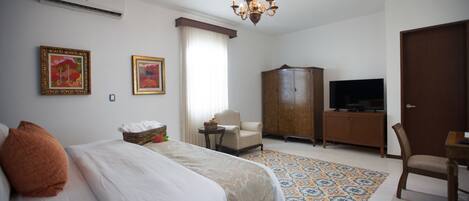 Una habitación de hotel con una cama, televisión, armario y una silla.