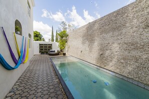 A swimming pool with a tiled deck and a brick wall. - Delfina Boutique Hotel (Mérida)
