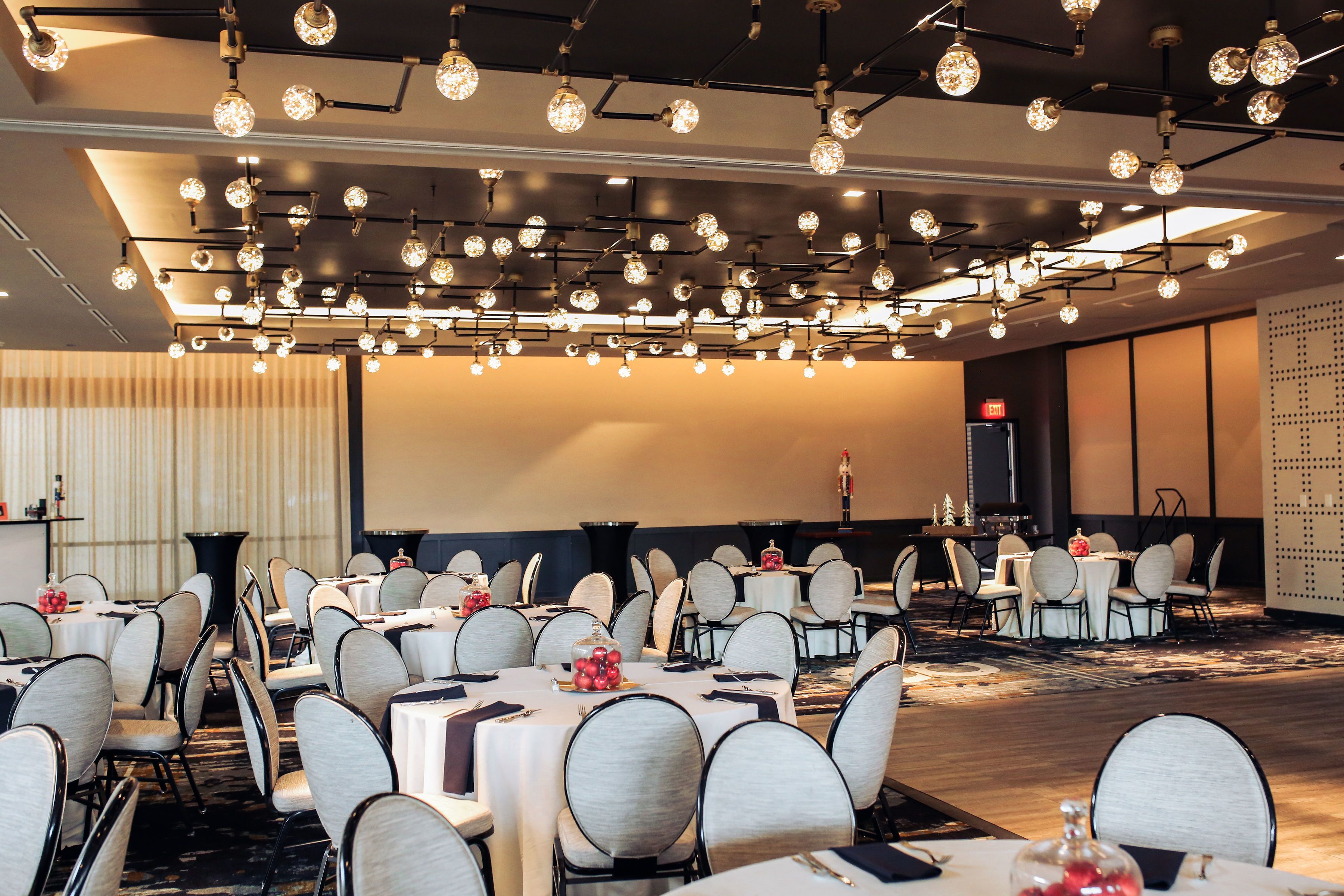 A conference room with round tables, chairs, and a modern chandelier.