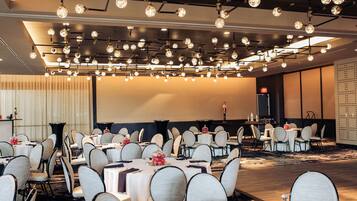 A conference room with round tables, chairs, and a modern chandelier.