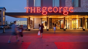A hotel entrance with a neon sign reading "THE GEORGE".