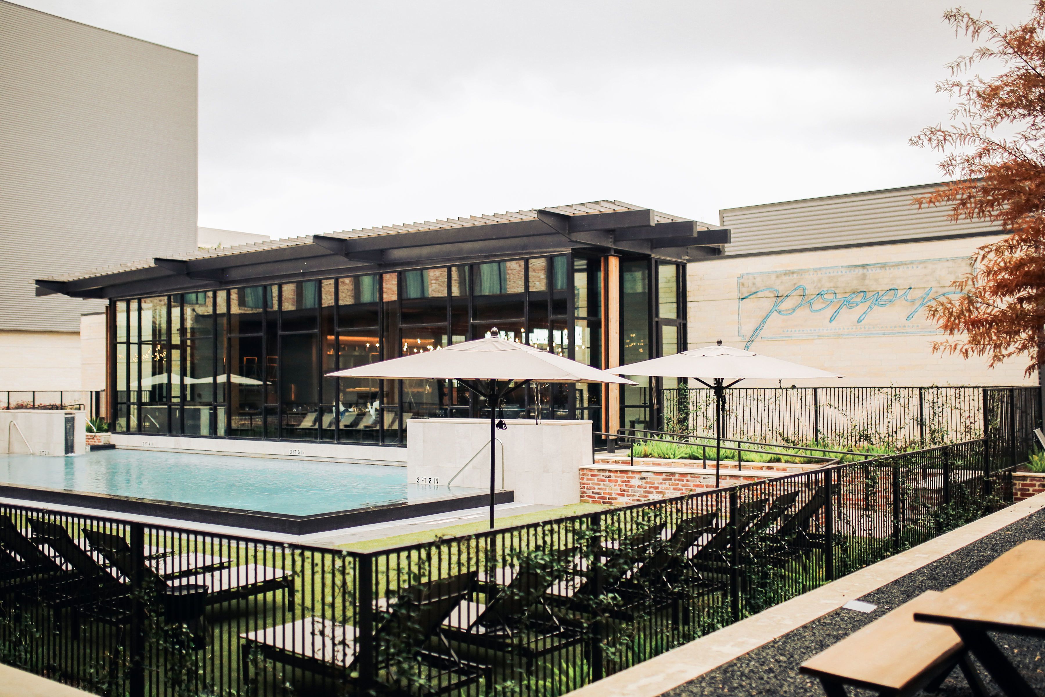 A modern building with a pool area, including lounge chairs and umbrellas.