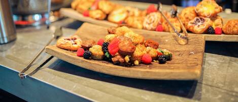 A variety of pastries on wooden boards, likely in a bakery or cafe setting.