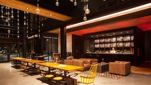 A modern bar area with a long wooden table, leather seating, and a red-lit bar counter.