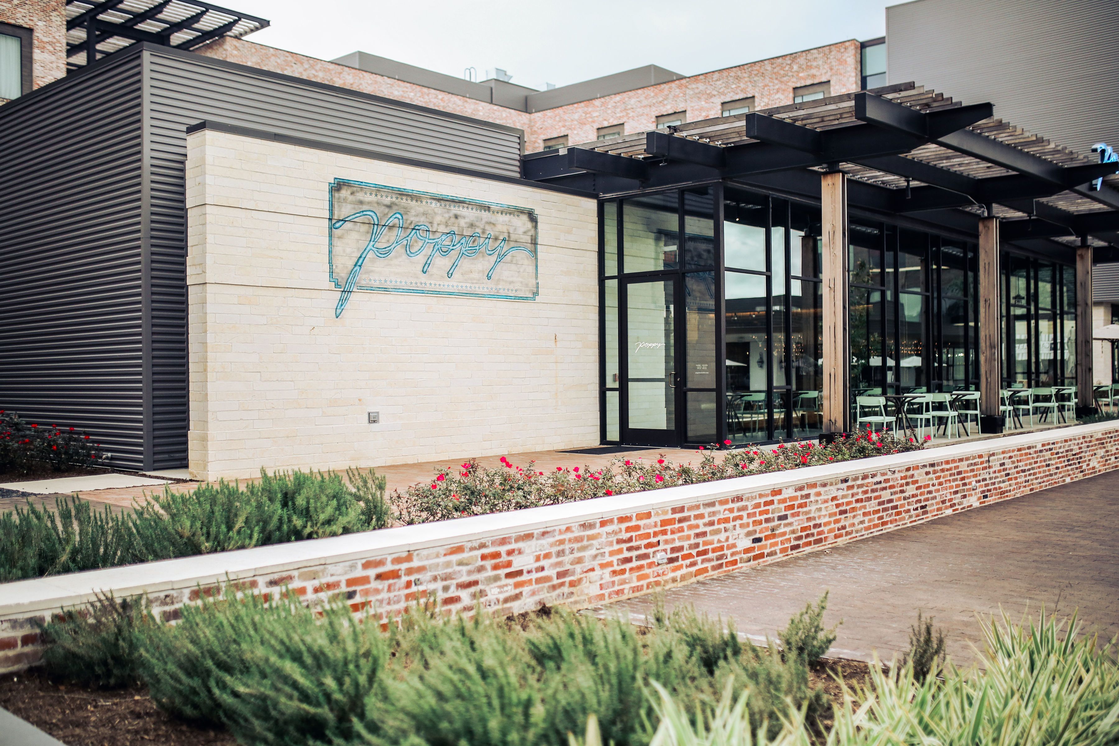 A building with a 'Doppy' sign, a brick wall, and a covered outdoor seating area with tables and chairs.
