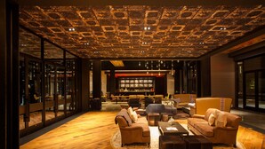 A modern interior with a wooden floor, a seating area with sofas and a coffee table, and a patterned ceiling.