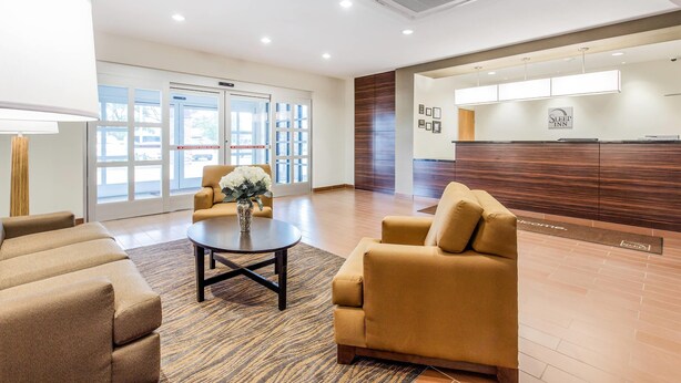 Eine moderne Lobby mit einer Rezeption, einer Sitzecke und großen Fenstern.