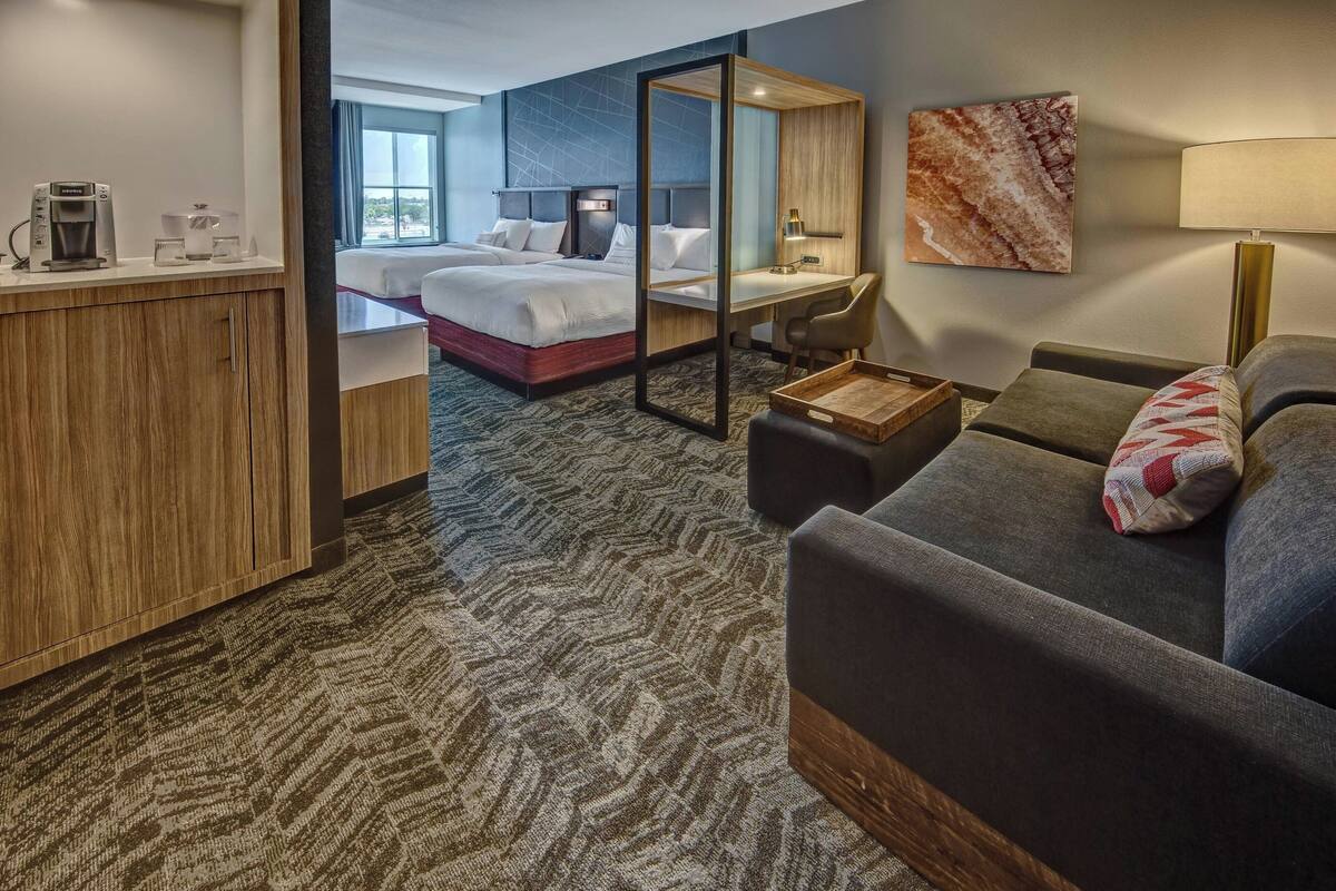 A hotel room with a bed, desk, and seating area.