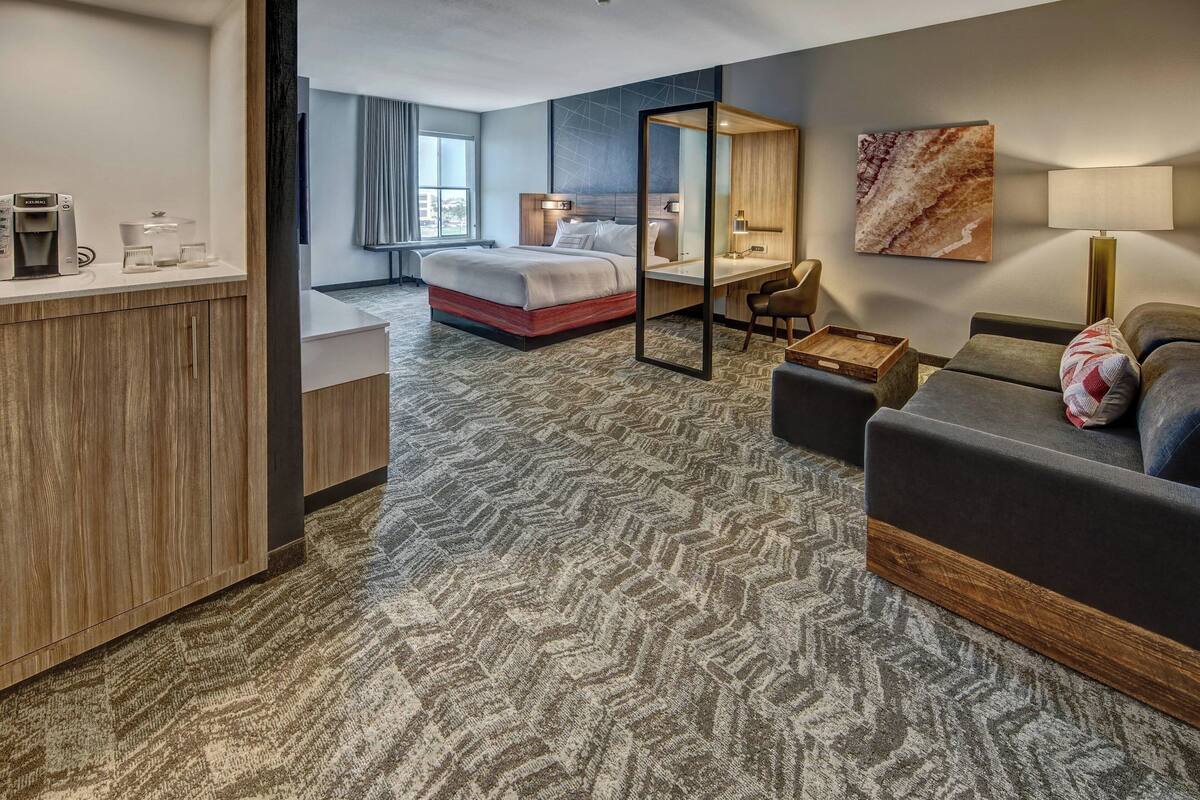 A hotel room with a bed, desk, and seating area.