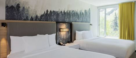 Et hotelværelse med to senge, et stort vindue med gule gardiner, en væglampe og et muralmaleri af en skov.