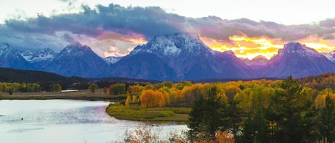 A mountainous landscape with a lake and autumn foliage.