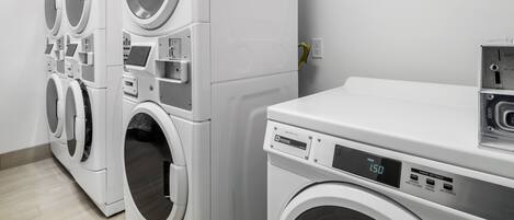 A laundry facility with multiple washing machines and dryers, including a digital display on one of the machines.