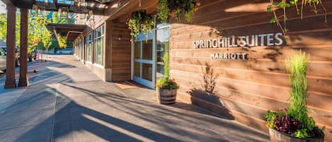 Un mur extérieur en bois portant l’inscription « SPRINGHILL SUITES MARRIOTT » et agrémenté de plantes en pot.