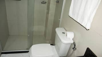 A bathroom with a glass shower enclosure, a toilet, and a sink.