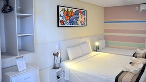 A hotel room with a bed, bedside tables, a wardrobe, and a painting on the wall.