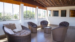 A spacious indoor area with wicker furniture, large windows, and a wooden ceiling.