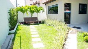 A well-maintained courtyard with a stone pathway, palm trees, and a building with large windows.