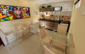 A compact kitchen with a dining area, featuring a microwave, coffee maker, and decorative tiles. - Hotel Pousada Elo Inn (Jaboatão dos Guararapes)