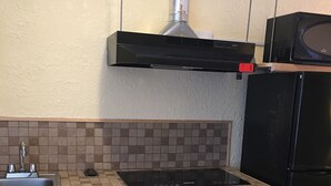 Una cocina con un lavamanos, estufa y refrigerador negro.