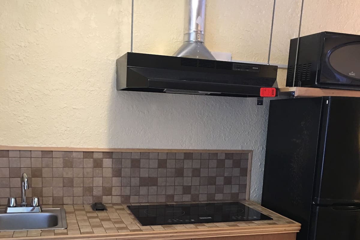 A kitchen with a sink, stove, and black refrigerator.