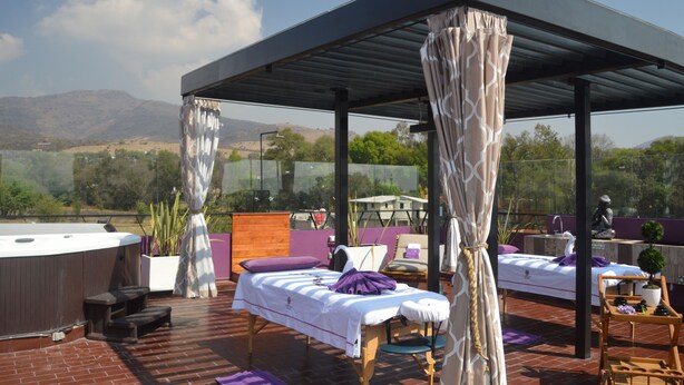 A rooftop spa with two massage tables, a hot tub, and a seating area.