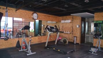 Un gimnasio con equipo de ejercicio, un reloj y un espejo.