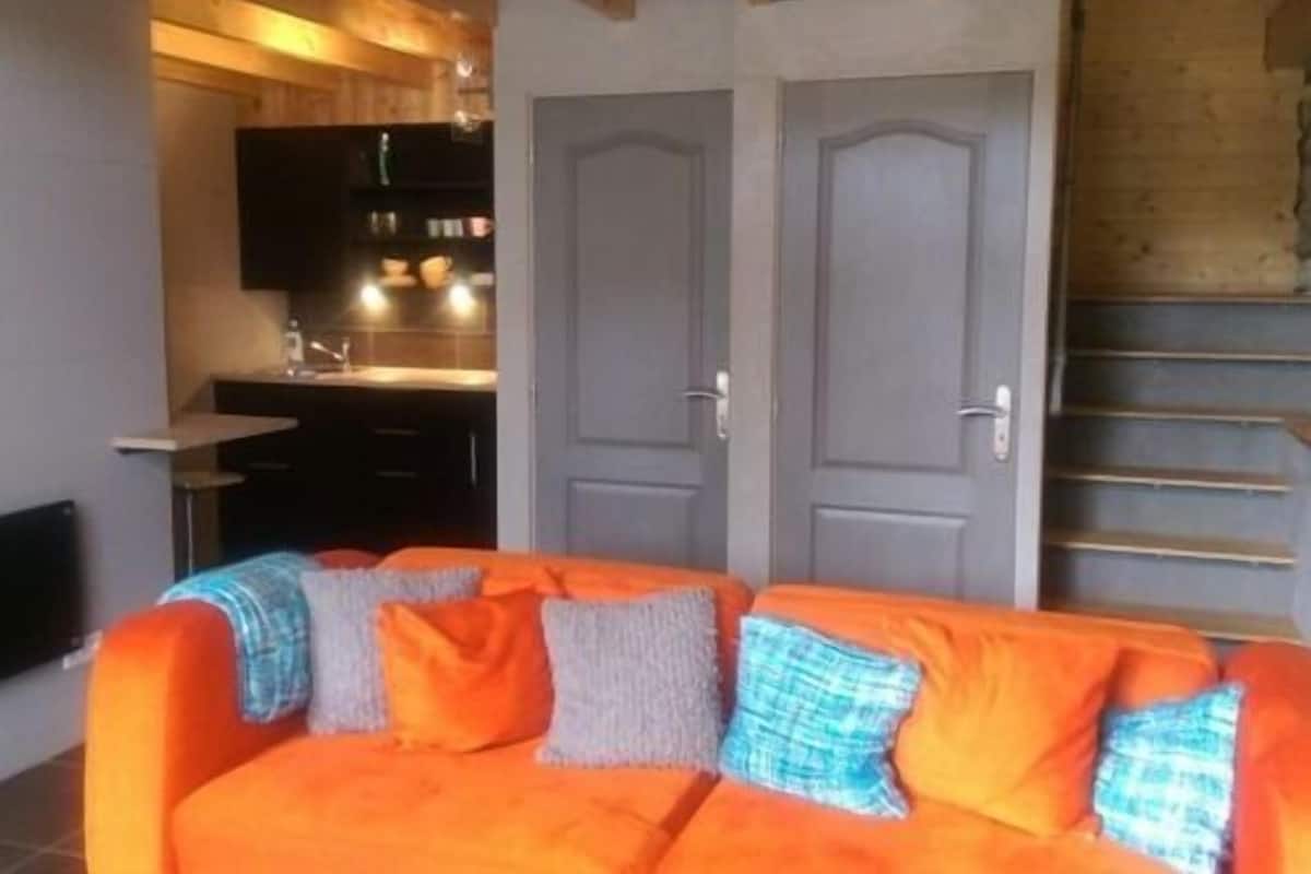 Una habitación con sofá, zona de cocina y escalera.