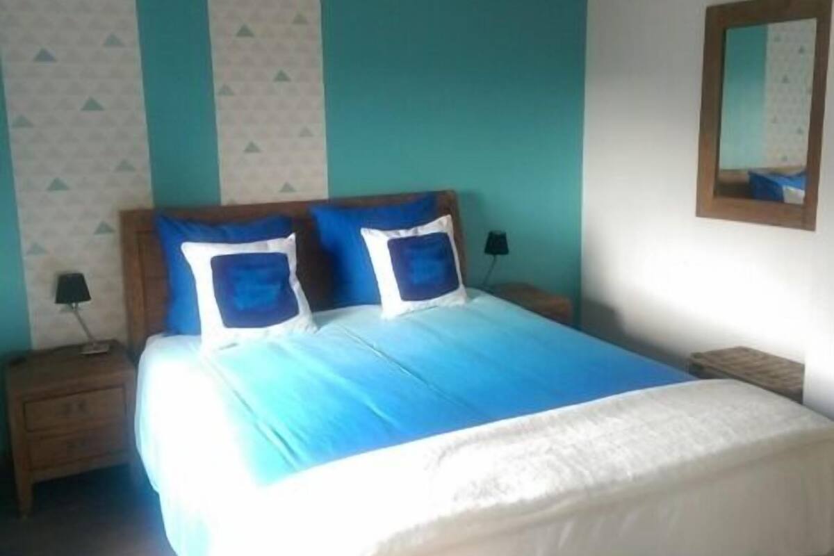 Un dormitorio con una cama, dos mesitas de noche y un espejo en la pared.