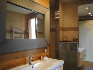 A modern bathroom with a large mirror, a white sink, and a glass shower enclosure. - Le Chalet Champenois (Bethon)