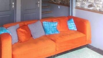 A room with a sofa against a wall, a stone feature, and a door.
