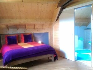 A wooden cabin bedroom with a bed, pillows, and a view of the outside. - Le Chalet Champenois (Bethon)