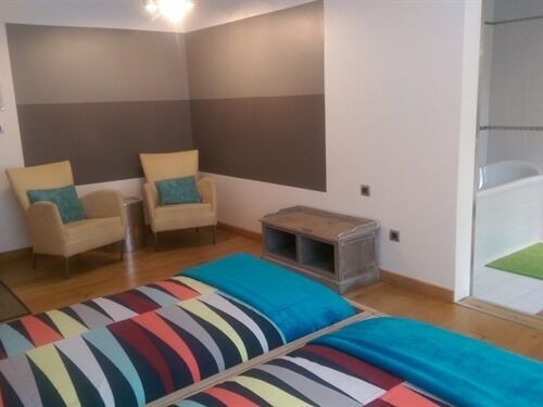 A room with two beds, two chairs, a small table, and a shower area.