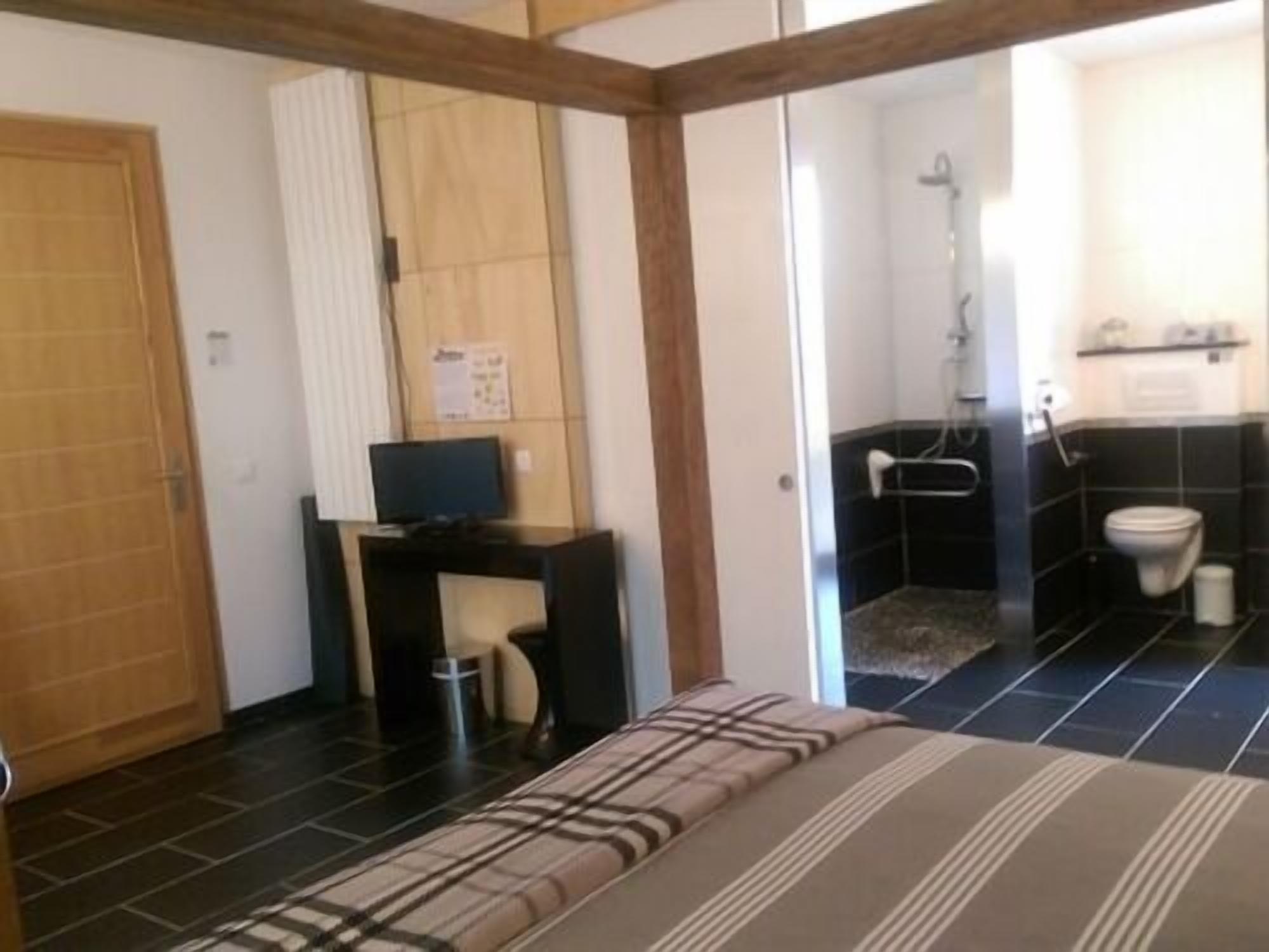 Een slaapkamer met een bed, een bureau met een computer, een douche en een toilet.