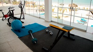 Un gimnasio con equipo de ejercicio, una colchoneta azul y una banca.