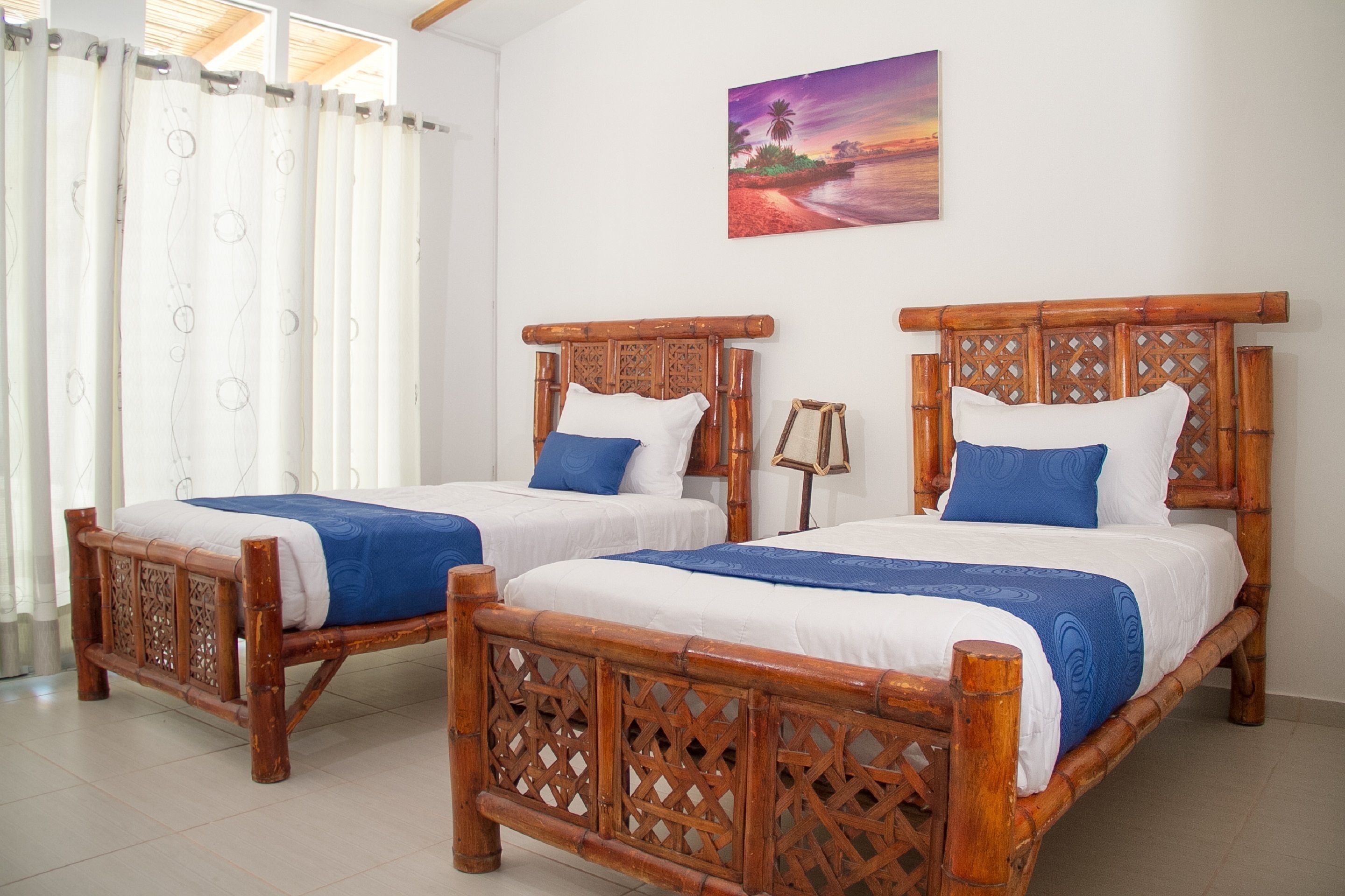 Two wooden beds with intricate lattice designs, white bedding, and blue accents.