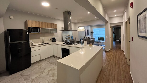 Una cocina moderna con una isla grande, electrodomésticos integrados y vistas al área de estar.