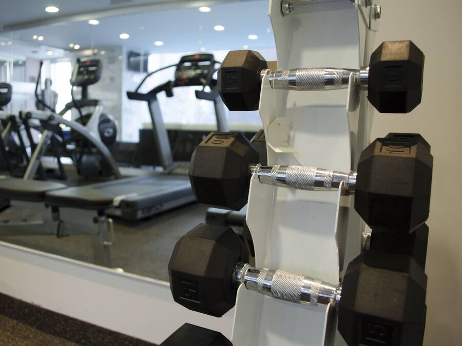 A gym with exercise equipment, including dumbbells and treadmills.