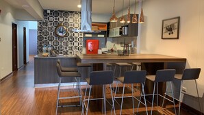 Una cocina moderna con una isla central, taburetes de bar e iluminación colgante.