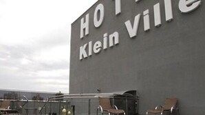 Zona de piscina de un hotel con sillas de descanso y un cartel que dice "HOTEL Klein Ville".