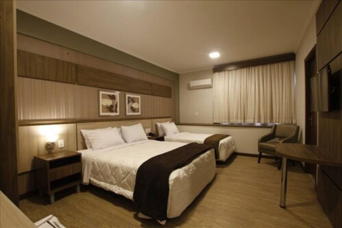 Habitación de hotel con dos camas, un escritorio, una silla y un televisor.