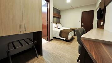 A compact hotel room with a bed, a desk, and a wardrobe.