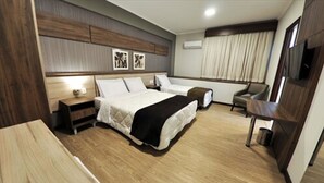 Una habitación de hotel con una cama grande, una mesita de noche, una silla y un escritorio.