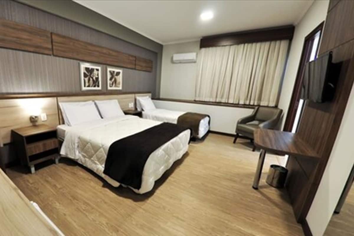 Una habitación de hotel con una cama grande, una mesita de noche, una silla y un escritorio.