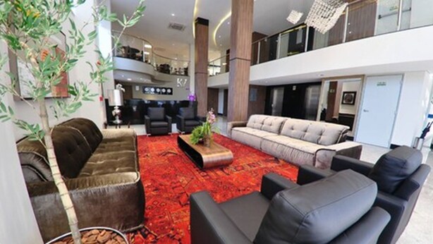 Un lobby moderno con alfombra roja, sofás de cuero y un pequeño árbol de interior.