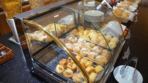Un bufé con diversos productos horneados y pasteles exhibidos en una vitrina.