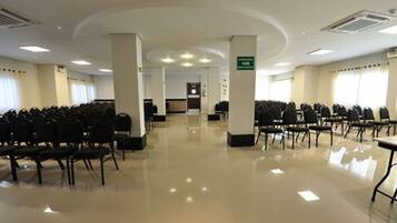 A spacious conference room with rows of chairs, a podium, and a sign indicating room number 145.