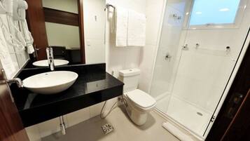 Un baño moderno con un lavabo grande de color blanco, un inodoro y una ducha con mampara de cristal.